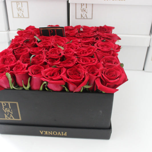 Pivonka Flores. Arreglo cuadrangular de 50 rosas rojas en base obscura. 